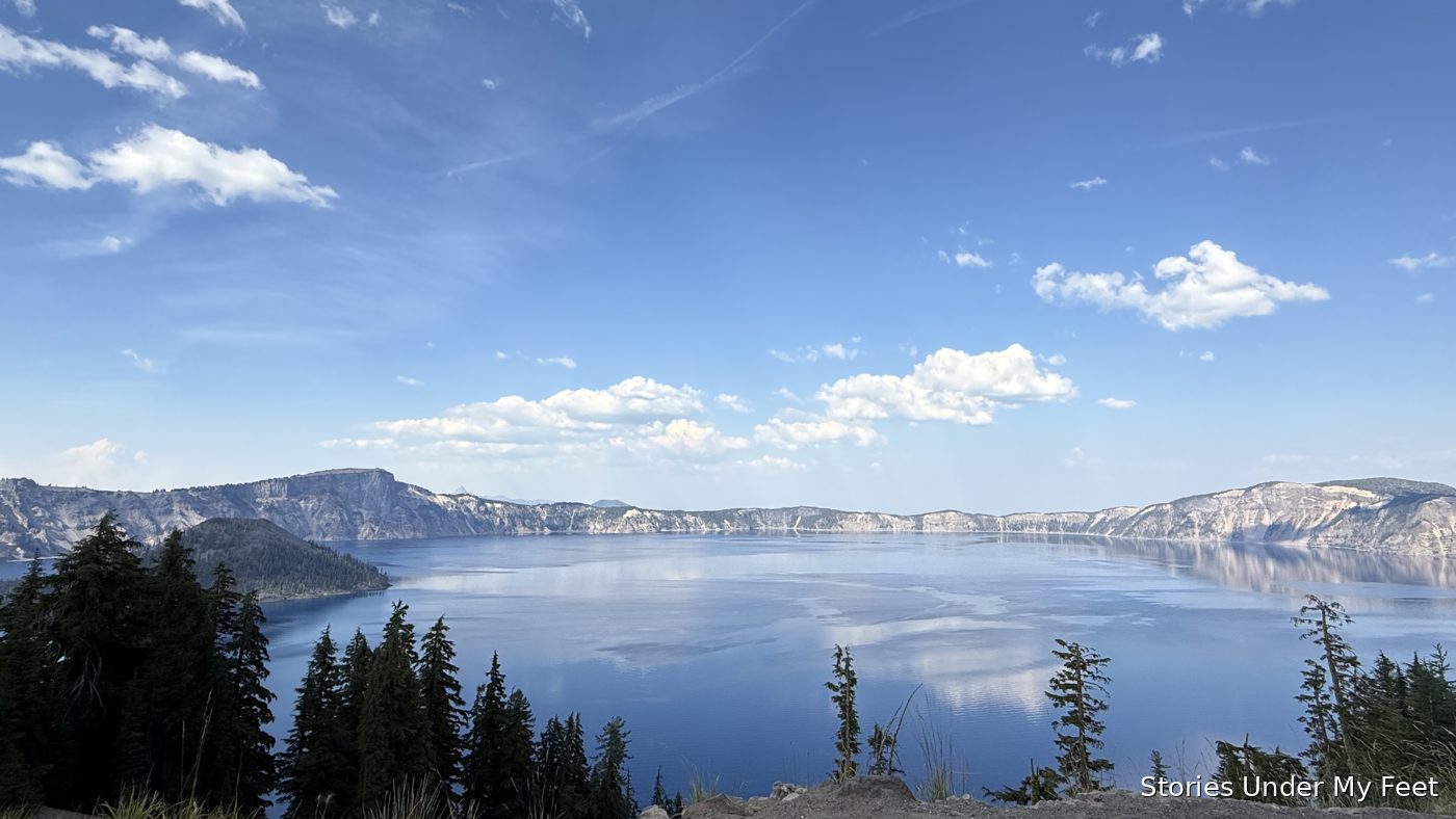 The lake as a glassy mirror, clouds and blue sky reflected across the still water